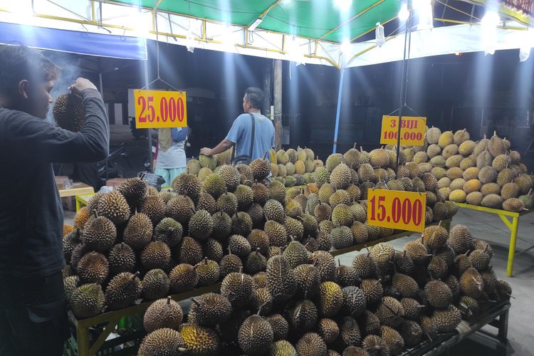 Salah seorang pembeli memilah durian obral Rp 15 ribu di perempatan Jl Kyai Turmudzi, Kabupaten Demak, Rabu (28/2/2024) malam. (KOMPAS.COM/NUR ZAIDI)
