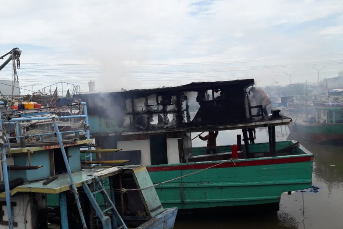 Petugas pemadam kebakaran berupaya memadamkan api yang melalap sebuah kapal di Pelabuhan Muara Angke, Senin (11/3/2019).