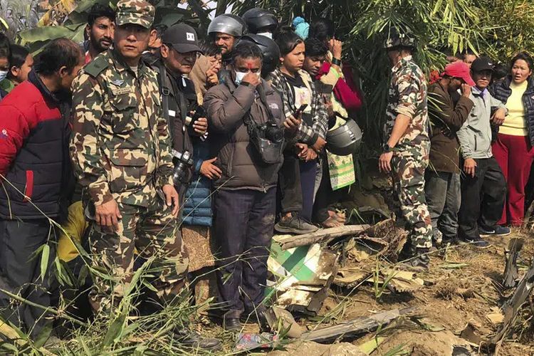 Warga menyaksikan reruntuhan pesawat penumpang di Pokhara, Nepal, Minggu, 15 Januari 2023. Sebuah pesawat penumpang dengan 72 orang di dalamnya jatuh di dekat Bandara Internasional Pokhara di Nepal, lapor surat kabar harian Kathmandu Post. Pesawat itu membawa 68 penumpang dan empat awak. 