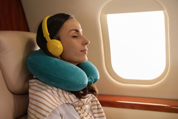 Ilustrasi penumpang pesawat mendengarkan lagu selama di pesawat.