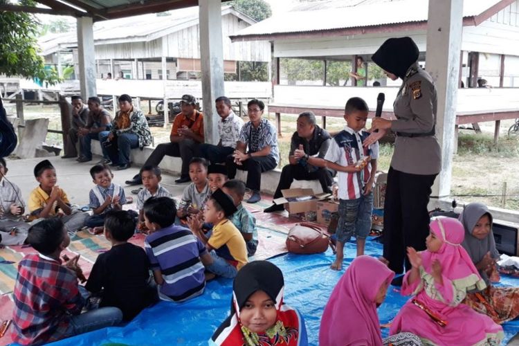 Polisi wanita menghibur anak-anak di lokasi ledakan sumur minyak Desa Pasir Putih, Kecamatan Rantau Peureulak, Kabupaten Aceh Timur, Jumat (4/5/2018).