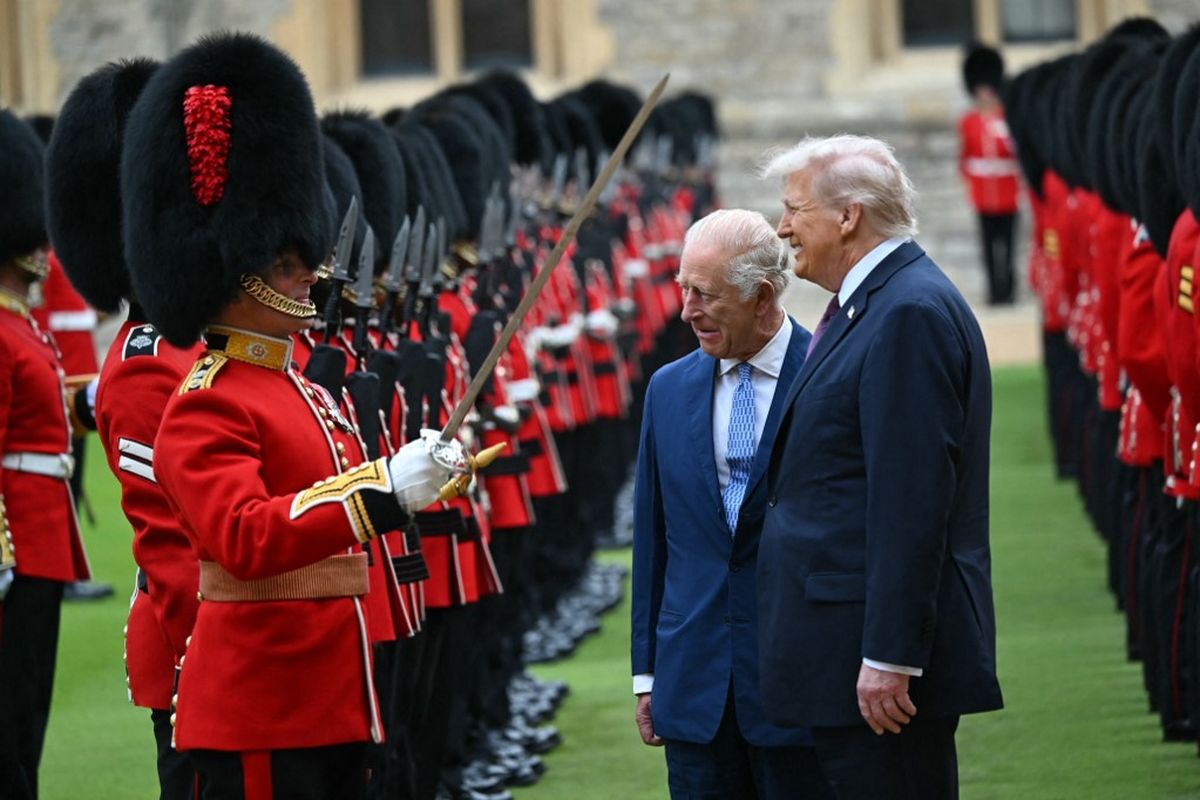 Raja Inggris Charles III (tengah) dan Presiden AS Donald Trump (kanan) berbicara dengan seorang anggota Garda Coldstream saat mereka memeriksa barisan kehormatan selama penyambutan seremonial di Quadrangle di Kastil Windsor, di Windsor, pada 17 September 2025, selama kunjungan kenegaraan Trump yang kedua. 