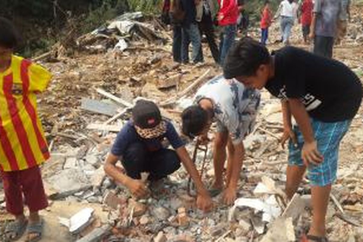 Anak-anak mengumpulkan besi bekas dari puinh-puing bongkaran rumah di Kampung Pulo, Jakarta Timur, Sabtu (22/8/2015).