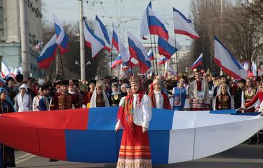 Warga kota Simferopol, Crimea membawa bendera Rusia saat merayakan lima tahun bergabungnya kembali semenanjung itu dengan Rusia.