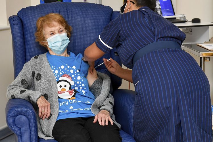 Foto tertanggal 8 Desember 2020 menunjukkan Margaret Keenan (90) menjadi pasien pertama di Inggris yang disuntik vaksin Covid-19 buatan Pfizer-BioNTech. Penyuntikan dilakukan oleh perawat May Parsons di University Hospital. Coventry, Inggris.