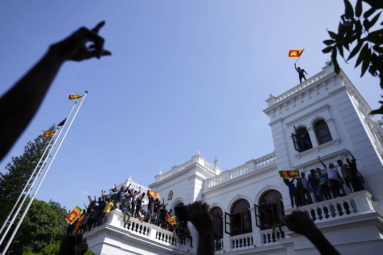 Seorang pedemo Sri Lanka mengibarkan bendera negara di atap kantor Perdana Menteri Ranil Wickremesinghe, dan menuntut pengunduran dirinya setelah Gotabaya Rajapaksa sebagai Presiden Sri Lanka melarikan diri ke Maladewa di tengah krisis ekonomi pada Rabu (13/7/2022).