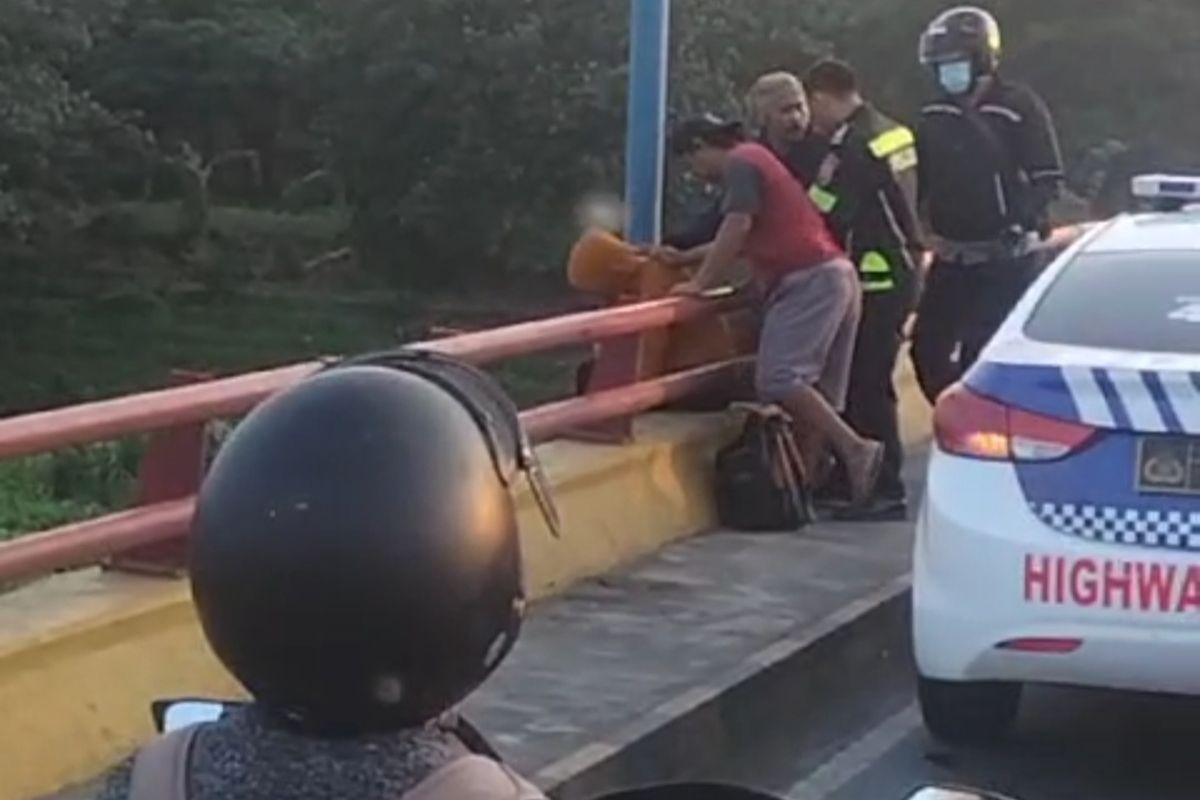 Warga dan petugas berupaya menggagalkan seorang pria yang hendak bunuh diri di jembatan Semampir, Kota Kediri, Jawa Timur, Senin (13/11/2023).