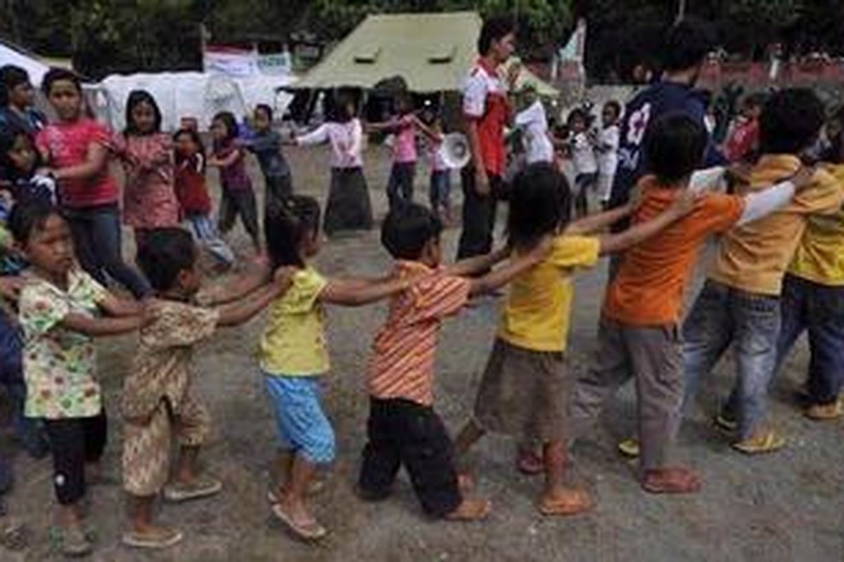 Puluhan anak-anak pengungsi korban letusan Gunung Merapi bermain bersama dipandu relawan-relawan Palang Merah Indonesia (PMI) di sekitar barak pengungsian Desa Dompol, Kecamatan Kemalang, Kabupaten Klaten, Jawa Tengah, Sabtu (30/10/2010). Dampak letusan Merapi membuat ratusan anak-anak turut mengungsi dan tidak dapat bersekolah. 