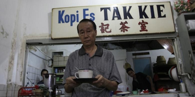 Pemilik kedai kopi es Tak Kie, Latif Yunus Membawa secangkir kopi di kedainya di kawasan Glodok, Jakarta Barat, Jumat (2/5/2014). Kedai kopi tua ini dirintis oleh Liong Kwie Tjong, kakek dari Latif Yunus sejak 1927. 