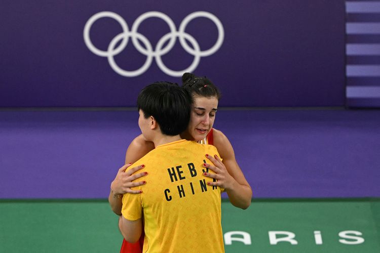 He Bing Jiao dari China (kuning) menghibur Carolina Marin dari Spanyol saat ia berjalan meninggalkan lapangan setelah mundur dalam pertandingan semifinal bulu tangkis tunggal putri mereka menyusul cedera pada Olimpiade Paris 2024 di Porte de la Chapelle Arena di Paris pada 4 Agustus 2024. (Foto oleh Arun SANKAR / AFP)