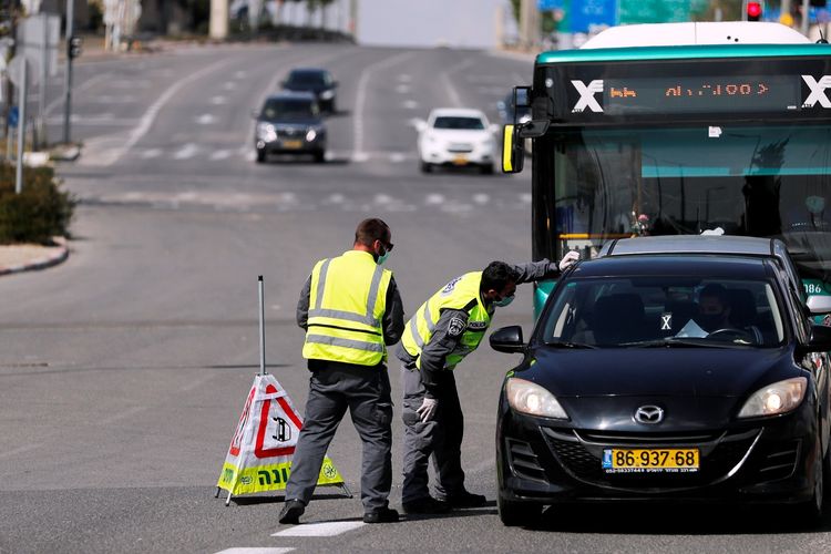 Polisi Israel melakukan pengecekan pada seorang pengendara mobil saat penutupan jalan utama, dalam upaya menahan penyebaran virus corona. Foto diambil pada 12 April 2020.