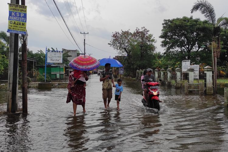 Sejumlah warga di Dukuh Kedung Banteng, Desa Wonorejo, Kecamatan Karanganyar menerjang banjir usai menyuarakan hak pilihnya di TPS SDN 2 Wonorejo, Sabtu (24/2/2024). (KOMPAS.COM/NUR ZAIDI)