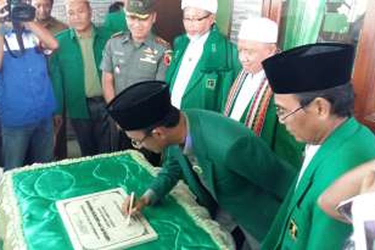 Politisi Demokrat Achmad Syafii menandatangani prasasti peresmian kantor PPP Pamekasan dikelilingi kiai PPP Pamekasan.