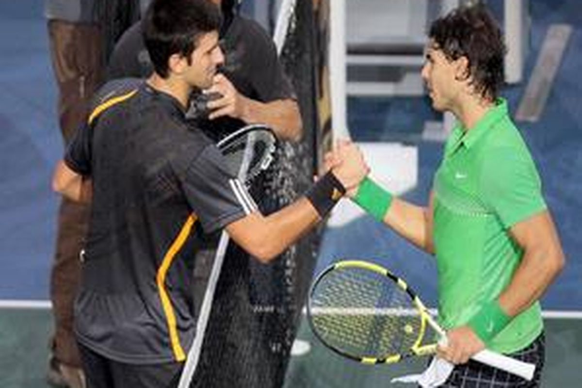 Novak Djokovic (kiri) bersalaman dengan Rafael Nadal yang ditaklukkannya di semifinal Paris Masters.