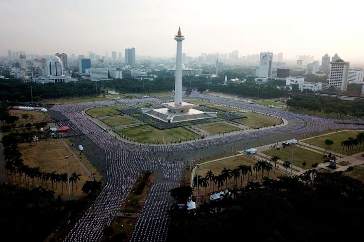 Ribuan warga melakukan senam poco-poco saat pemecahan rekor dunia senam massal poco-poco di Monas, Jakarta, Minggu (5/8/2018). Kegiatan dalam rangka menyambut Asian Games 2018 itu diikuti 65 ribu peserta dari berbagai kalangan.