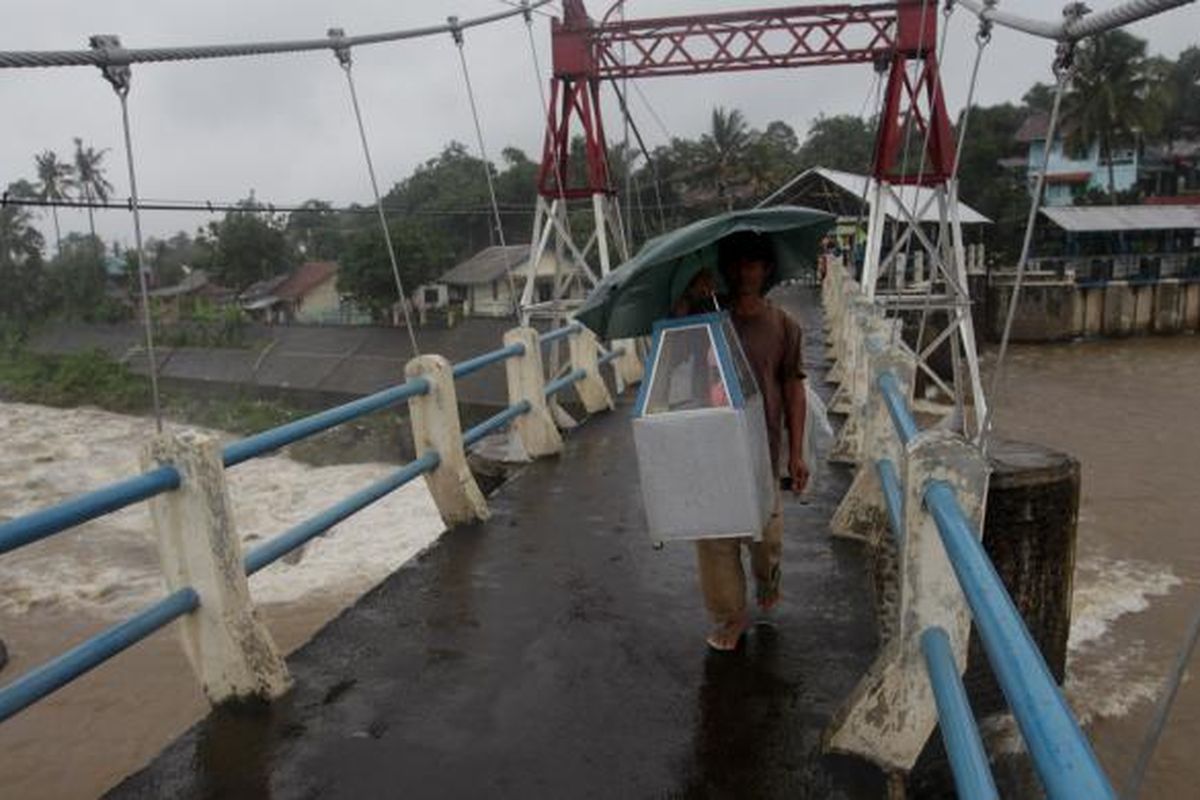 Warga melintas Bendungan Katulampa, Bogor, Jawa Barat, saat hujan lebat mengguyur Bogor, Rabu (9/1/2013). Ketinggian air di Bendungan Katulampa mencapai 120 sentimeter melebihi batas normal yaitu 50 sentimeter sehingga ditetapkan status siaga tiga. Warga terutama yang tinggal di daerah bantaran-bantaran sungai dihimbau bersiaga dan mengantisipasi datangnya banjir. KOMPAS IMAGES/KRISTIANTO PURNOMO