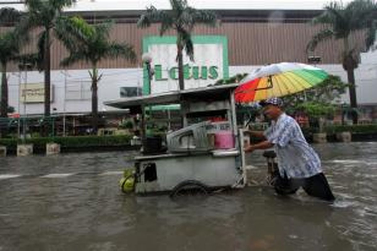 Pedagang melintasi di Jalan Wahid Hasyim, Jakarta Pusat, yang terendam banjir, Senin (9/5/2015). Drainase yang buruk dan hujan yang mengguyur sejak semalam mengakibatkan sejumlah jalan protokol di Jakarta Pusat terendam air.