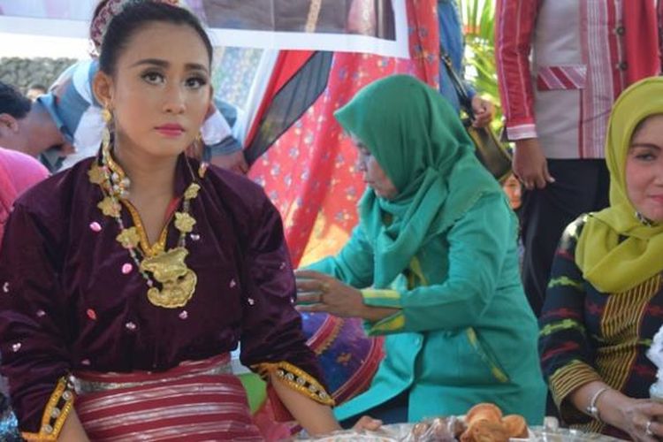 Seorang wanita menggunakan baju adat Buton melayani para warga yang hendak memakan isi talang. Pemerintah Kota Baubau, Sulawesi Tenggara menggelar seribu talang yang berisikan makanan berat di sekeliling Benteng Keraton Kesultanan Buton, Senin (17/10/2016).