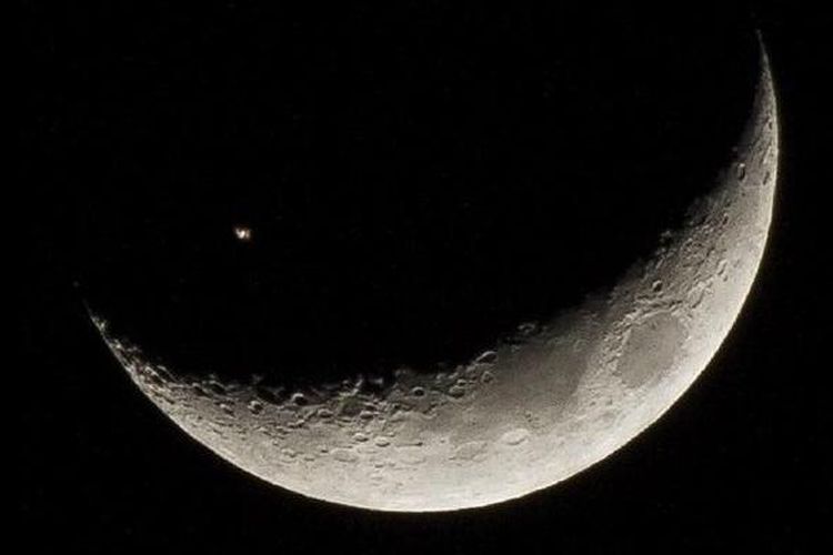 Stasiun Luar Angkasa Internasional (ISS) terpotret melintasi bulan sabit. 