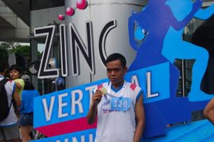 Salah satu peserta vertical running, Dian Prasetyo berfoto dengan finisher medal yang ia dapatkan usai finis di puncak menara BCA, Sudirman, Jakarta, Minggu (13/10/2013).