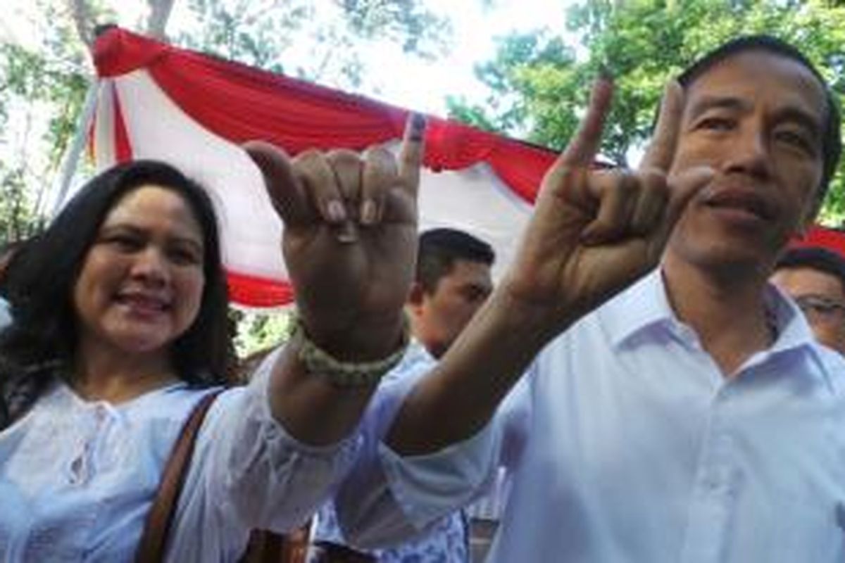 Gubernur Jakarta Joko Widodo dan sang istri Iriana memamerkan jari kelingkingnya usai menggunakan hak suara di TPS 27, Menteng, Jakarta Pusat, Rabu (9/4/2014).