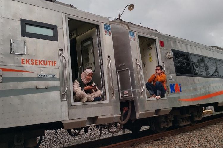 Sejumlah penumpang terlihat duduk di pintu KA Turangga Surabaya-Bandung. Kereta mereka tertahan 12 jam akibat rel ambles di tiga titik. 