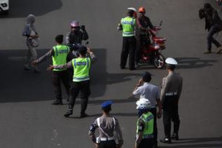 Gabungan petugas kepolisian dan Dinas Perhubungan DKI mengarahkan pengendara sepeda motor yang akan melintas di Jalan MH Thamrin, Jakarta Pusat, Rabu (17/12/2014). Di hari pertama uji coba pembatasan sepeda motor sepanjang Jalan Thamrin-Medan Merdeka Barat, masih terdapat sejumlah pengendara yang belum mengetahui aturan tersebut. KOMPAS/LUCKY PRANSISKA 