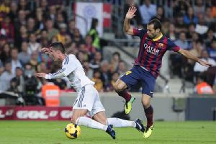 Gelandang Real Madrid Cristiano Ronaldo berebut bola dengan gelandang Barcelona Javier Mascherano, pada laga Liga BBVA, di Camp Nou, 26 Oktober 2013. 