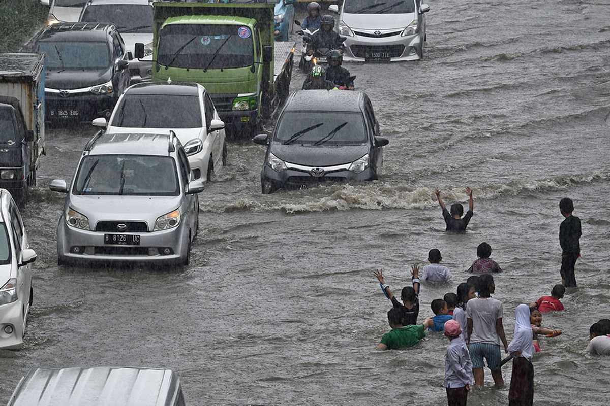 Sejumlah pengendara kendaraan bermotor melintasi Jalan Gunung Sahari yang mengalami banjir di Pademangan, Jakarta, Jumat (24/1/2020). Hujan yang mengguyur sejak Jumat pagi hingga siang hari tersebut memicu banjir setinggi 30-50 centimeter di jalan raya itu sehingga menyebabkan lalu lintas kendaraan bermotor dan roda perekonomian warga setempat tersendat.
