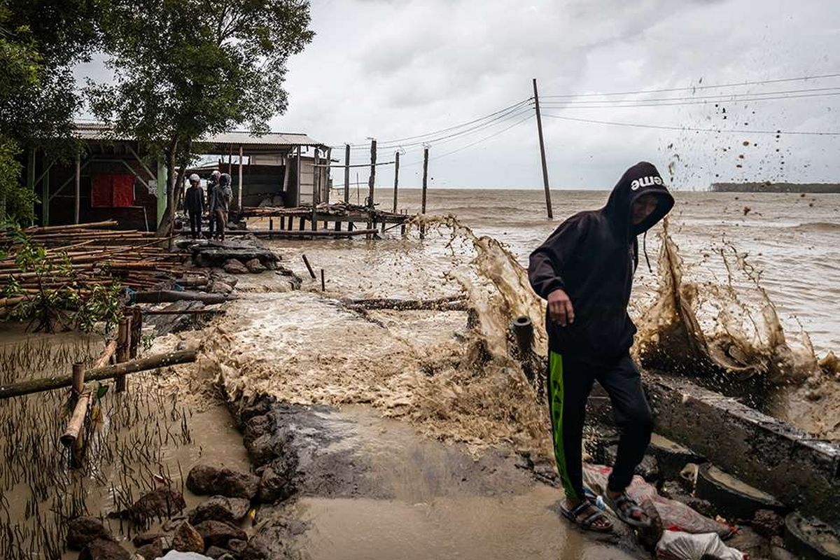 Warga menembus jalan desa yang rusak akibat terjangan gelombang tinggi air laut di Desa Bedono, Sayung, Demak, Jawa Tengah, Senin (7/12/2020). BMKG mengeluarkan peringatan dini gelombang tinggi setinggi 2,5 - 4 meter dengan kecepatan angin 30 knot yang berpeluang terjadi pada Senin (7/12) - Rabu (9/12) di sejumlah wilayah perairan dan pesisir di Indonesia di antaranya yaitu laut Jawa bagian tengah, dengan imbauan kepada nelayan maupun warga yang bermukim di daerah tersebut agar waspada saat beraktivitas.