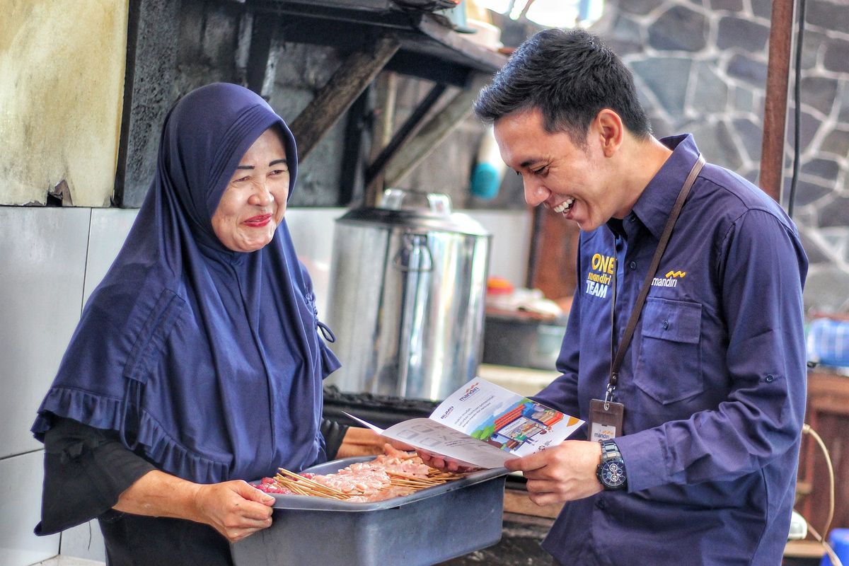 Pekerja Bank Mandiri menyosialisasikan produk perbankan kepada pelaku UMKM.