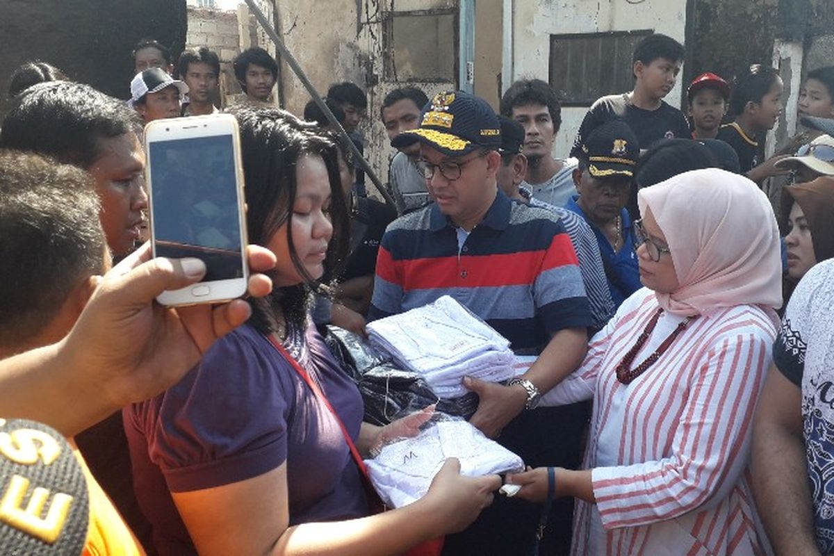 Gubernur DKI Jakarta Anies Baswedan dan istri memberikan bantuan seragam sekolah kepada korban kebakaran di Taman Kota, Kembangan, Jakarta Barat pada Jumat (30/3/2018). 