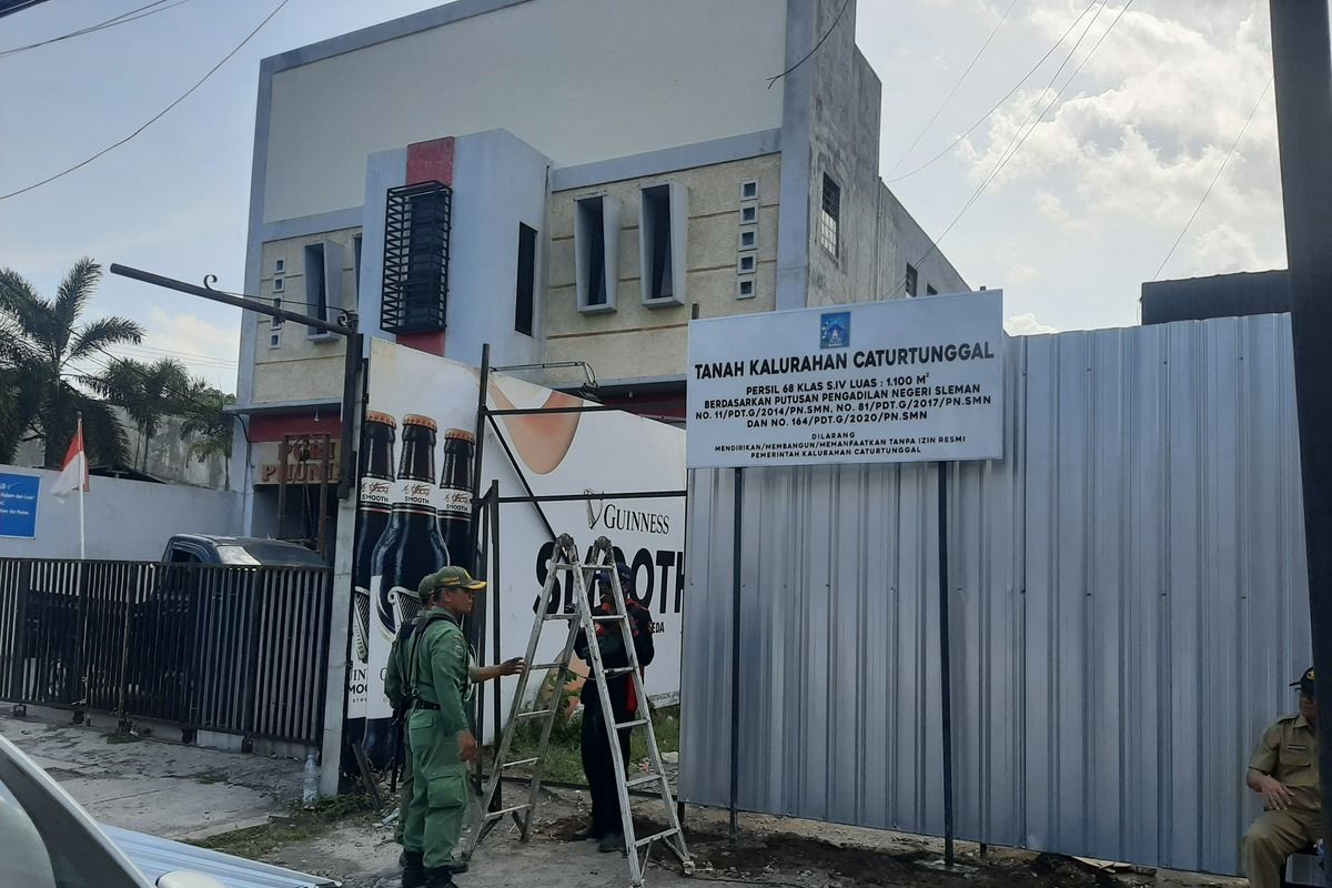 Petugas saat menutup akses masuk ke tanah kas desa Caturtunggal di daerah Babarsari dengan seng. Di dalam seng tersebut berdiri bangunan cafe yang tidak memiliki izin menempati tanah kas desa.