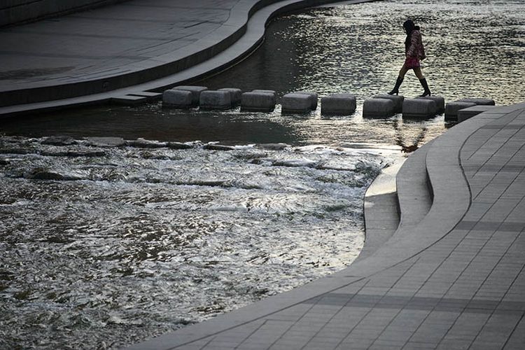 Seorang warga Seoul menyeberangi aliran Cheonggyecheon di Seoul. Aliran sungai buatan tersebut sebagai hasil restorasi yang dikerjakan pada 2003-2005.