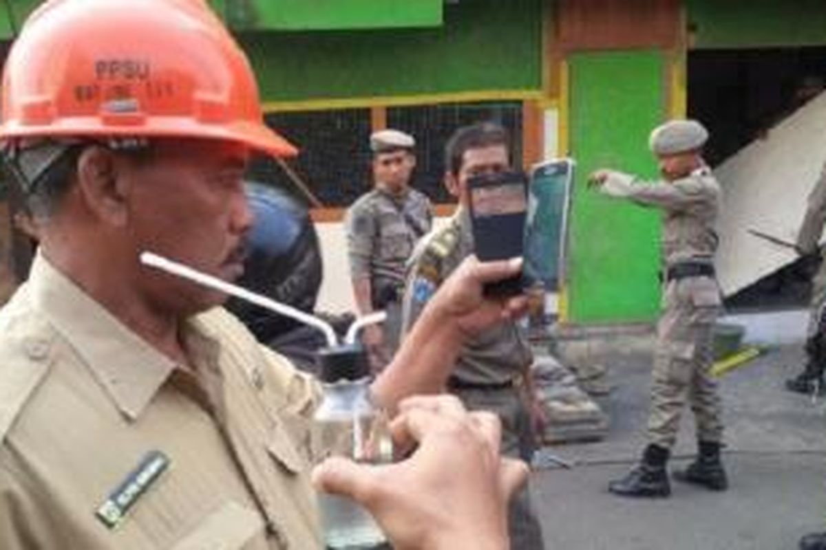 Petugas menunjukkan bong atau alat isap sabu di antara bangunan liar yang dibongkar di Jalan Tanjung Duren Utara, Grogol Petamburan, Jakarta Barat, Selasa (22/9/2015).