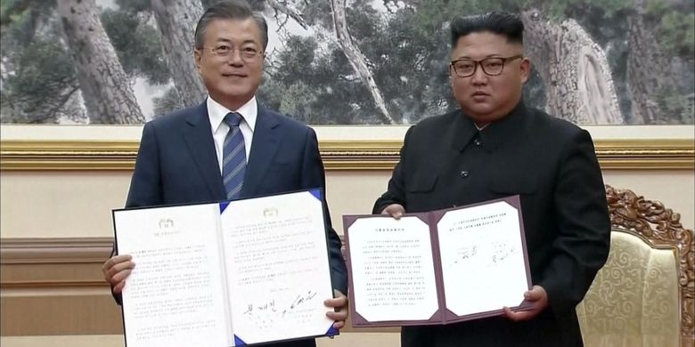 Presiden Korea Selatan Moon Jae-in (kiri) dan Pemimpin Korea Utara Kim Jong Un menunjukkan deklarasi yang mereka tandatangani dalam pertemuan di Pyongyang. Kim sepakat untuk menutup situs uji coba rudalnya.