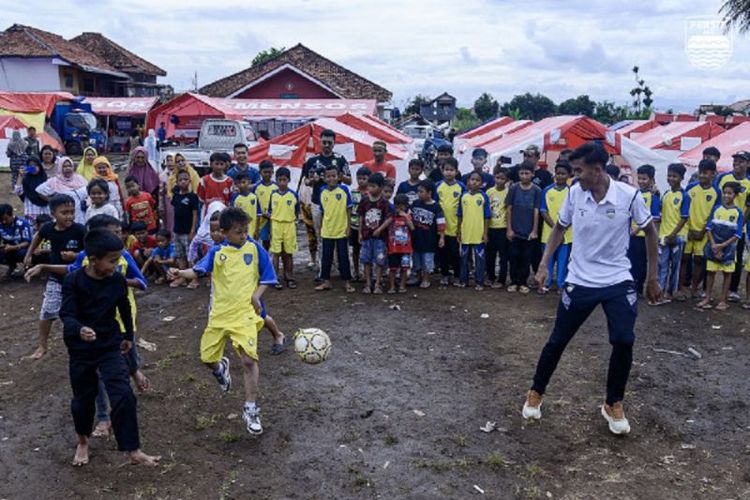 Dua pemain Persib Bandung, Kakang Rudianto dan Robi Darwis, bermain sepak bola bersama anak-anak korban gempa Cianjur, Jumat (2/12/2022). Kegiatan yang digelar di Lapangan Jagakarsa, Warungkondang, Kabupaten Cianjur, ini merupakan rangkaian program Sauyunan yang diadakan Persib Bandung.