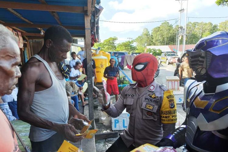 Anggota kepolisian dengan menggunakan kostum super hero saat memberikan sosialisasi Covid-19 kepada warga di Distrik Mimika Timur, Mimika, Papua, Minggu (26/4/2020).