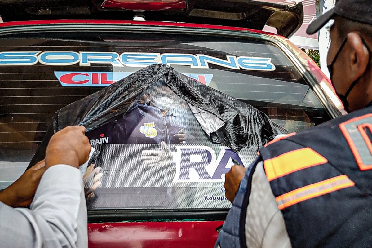 Petugas Dishub Bandung Barat mencabut paksa stiker kampanye yang menutupi kaca angkot, Kamis (10/8/2023).
