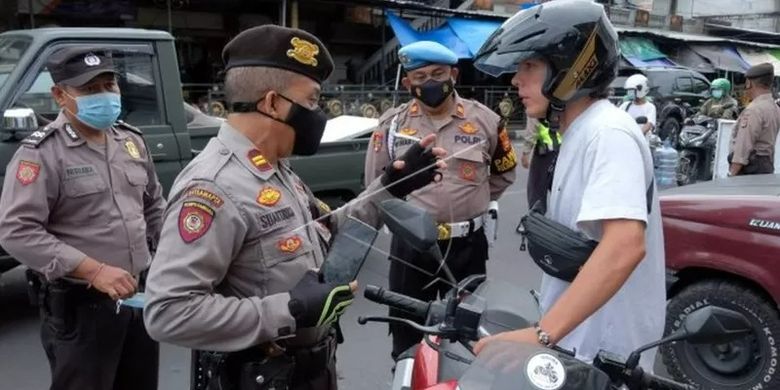 Polisi menegur warga negara asing (WNA) yang tidak mengenakan masker saat razia masker di Denpasar, Bali, Sabtu (5/2/2022).