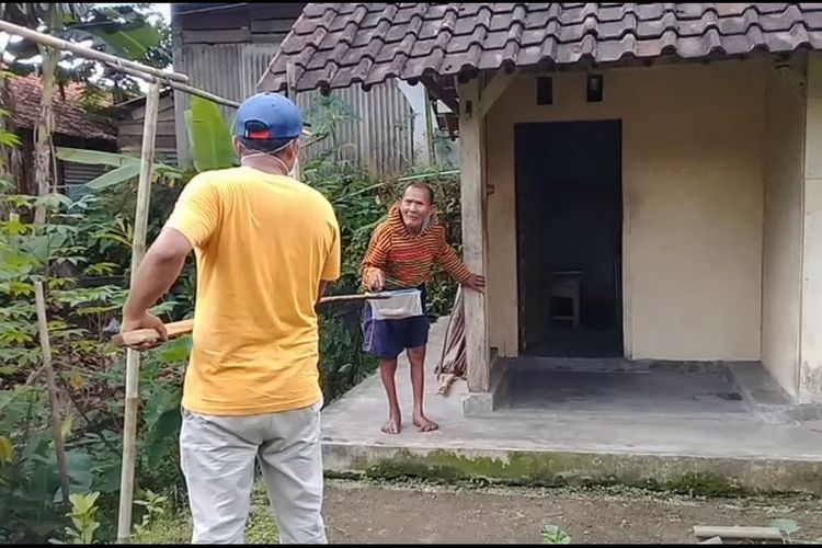 Relawan memberikan batuan sembako dan uang tunai menggunakan galah bambu kepada warga Dusun Bawahan, Desa Gunungwuled, Kecamatan Rembang, Purbalingga, Jawa Tengah, Selasa (31/3/2020).