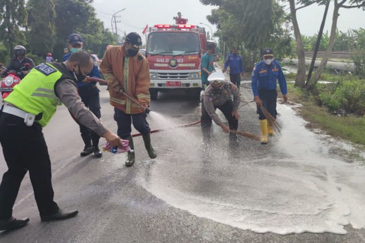 Pihak kepolisian bersama petugas pemadam kebakaran Lamongan, saat membersihkan jalanan dari tumpahan cairan kimia yang tercecer.