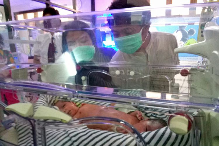 Pasangan suami istri Azis (34) dan Dini Pertiwi (34) tengah melihat bayinya yang terlahir kembar siam dalam sebuah inkubator di RSHS Bandung. 