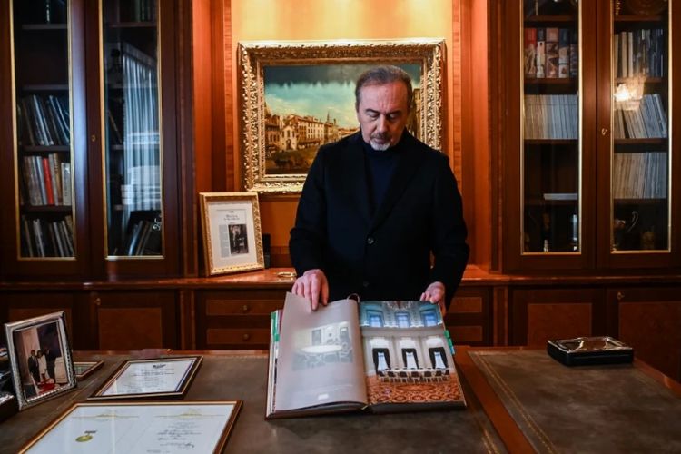 Renato Pologna, pembuat meja panjang Putin, menunjukkan buku terbitan 1999 yang memperlihatkan foto meja sama dengan yang di Kremlin, Moskwa, Rusia.