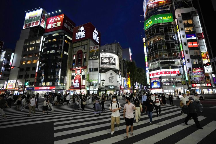 Orang-orang berjalan di sepanjang penyeberangan pejalan kaki Jumat, 30 Juli 2021, di Tokyo, ketika Perdana Menteri Jepang Yoshihide Suga memperluas keadaan darurat virus corona ke empat wilayah lagi selain Tokyo menyusul rekor lonjakan infeksi saat ibu kota menjadi tuan rumah Olimpiade.
