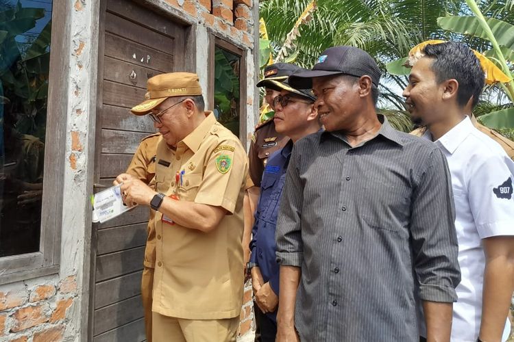 Pj Bupati PPU Makmur Marbun menempelkan stiker khusus di rumah-rumah warga penerima manfaat BPJS Ketenagakerjaan, Selasa (30/1/2024).