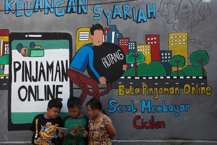 Sejumlah anak membaca bersama di dekat dinding bermural di kawasan Tempurejo, Surabaya, Jawa Timur, Selasa (7/9/2021). Mural tersebut sebagai sarana imbauan kepada masyarakat terhadap bahaya pinjaman daring atau 'online' (pinjol) ilegal yang sekarang lagi marak. ANTARA FOTO/Didik Suhartono/hp.