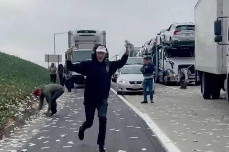 Tangkapan layar dari video Instagram @demibagby yang memperlihatkan warga Amerika Serikat ramai-ramai memunguti hujan uang di jalan tol Interstate 5 dekat Cannon Road, kota Carlsbad, negara bagian California, Jumat pagi (19/11/2021) waktu setempat. Uang kertas berhamburan keluar dari mobil lapis baja yang tas pembawanya rusak dan pintunya terbuka.