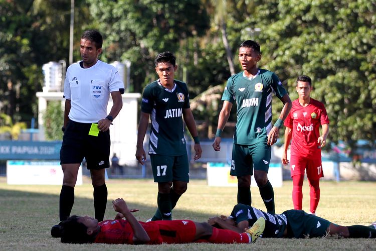 Pemain Jawa Timur dan Aceh terjatuh seusai berebut bola saat semifinal PON XX Papua 2021 yang berakhir dengan skor 1-2 di Stadion Barnabas Youwe Sentani Kabupaten Jayapura, Selasa (12/10/2021) sore.