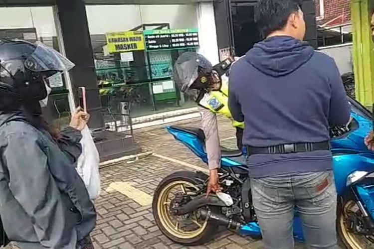 Anggota kepolisian menunjuk knalpot racing sepeda motor yang disebut ditilang saat baru beli dari dealer, Kamis (24/6/2022) siang.